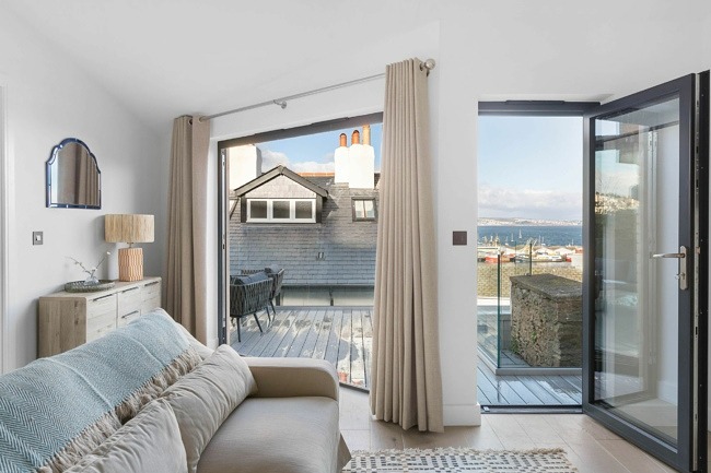 Seating area with doors opening to decking with sea view - The Sail Loft Suite