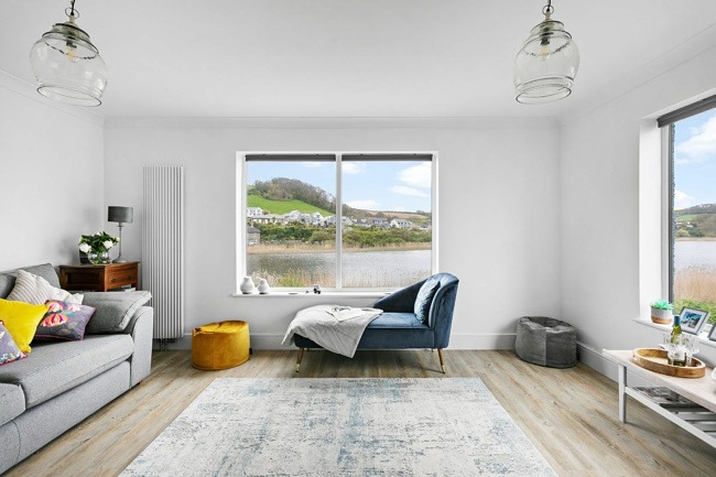 Open lounge area with large window overlooking water - Swans nest