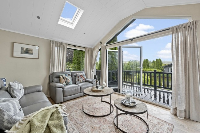 Living area with coffee table, sofas, TV, decking area with hot tub - Brayford Lodge, Kentisbury Grange