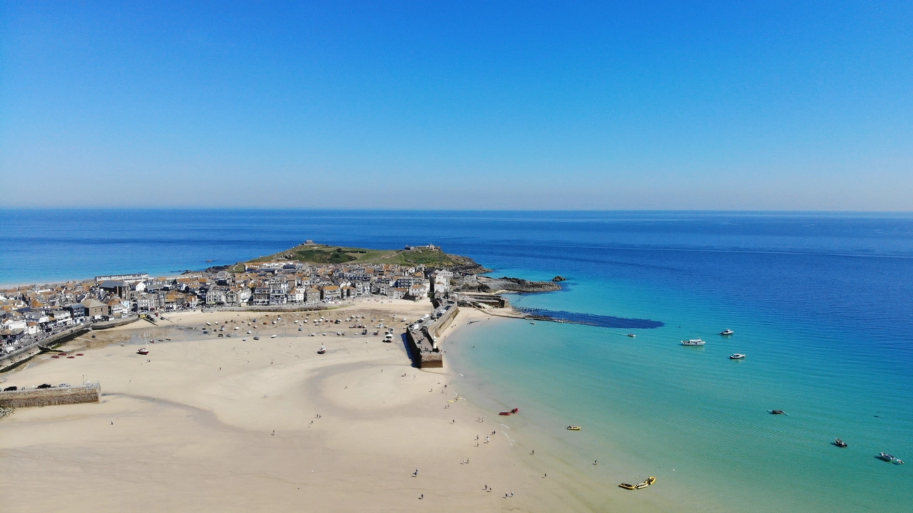 Beautiful drone views over white sand and turquoise water of St Ives harbour in Cornwall