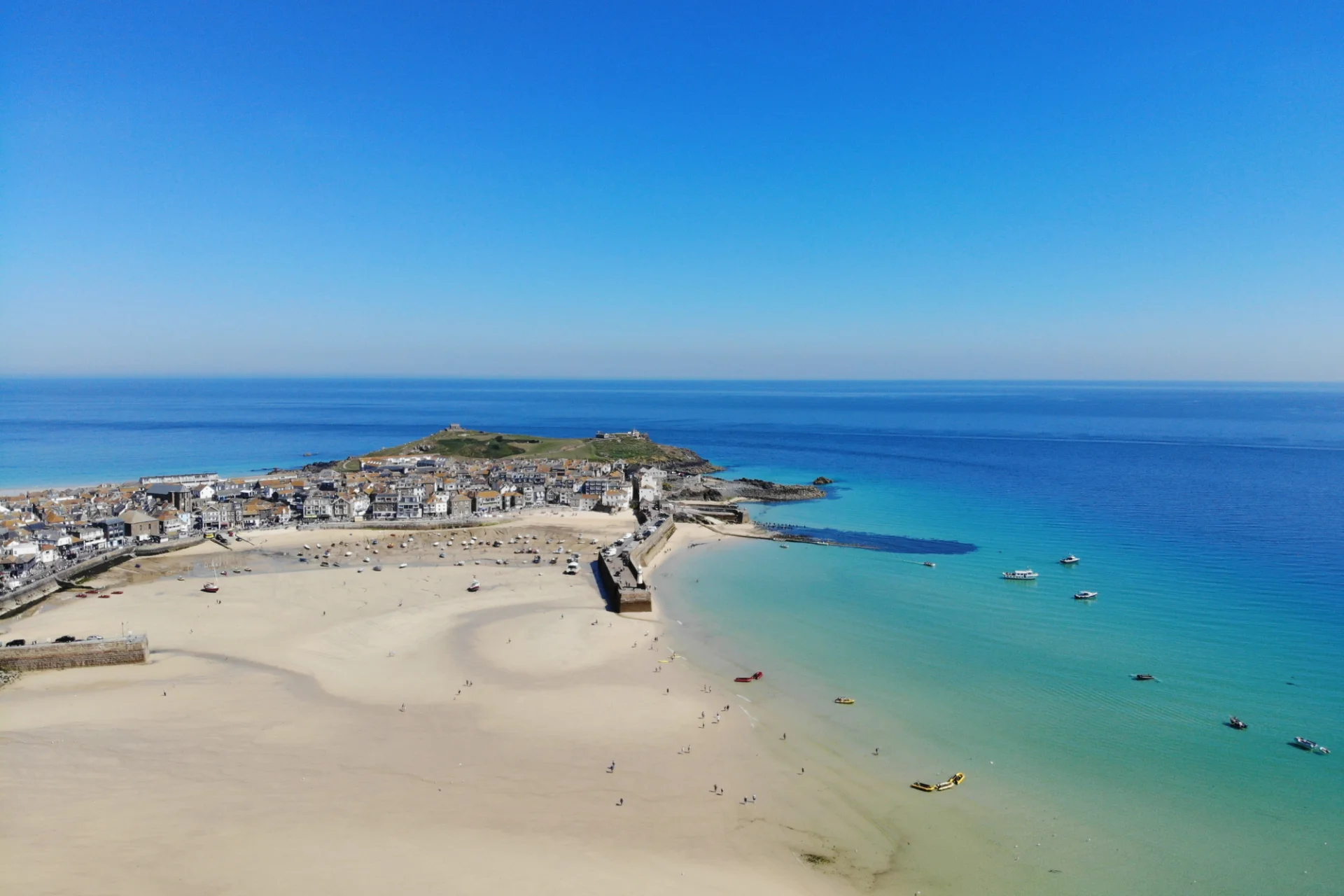 Beautiful drone views over white sand and turquoise water of St Ives harbour in Cornwall
