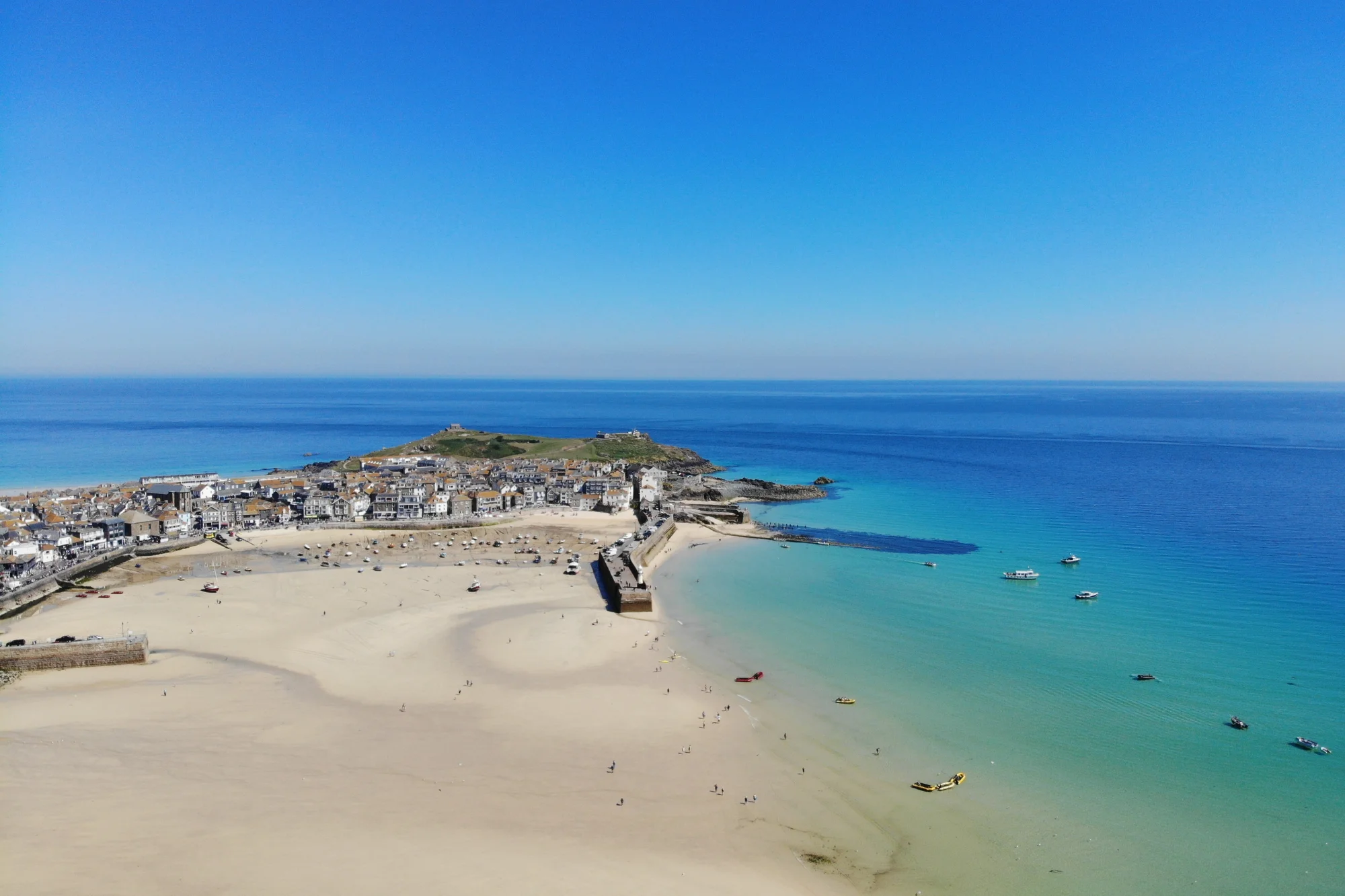 Beautiful drone views over white sand and turquoise water of St Ives harbour in Cornwall