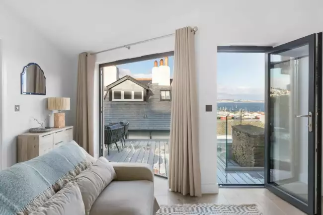 Seating area with doors opening to decking with sea view - The Sail Loft Suite